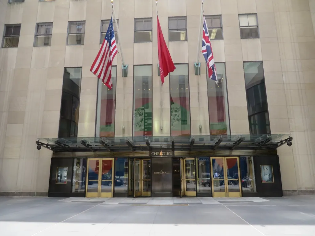 Entrance of Christie's at 20 Rockefeller Plaza in New York, with the American, Christie's and British flags above the glass canopy